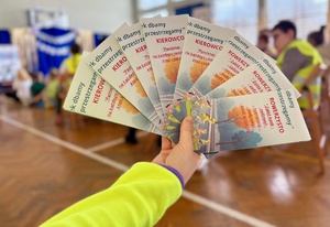 Ulotki dla rowerzystów i kierowców samochodów trzymane w ręce