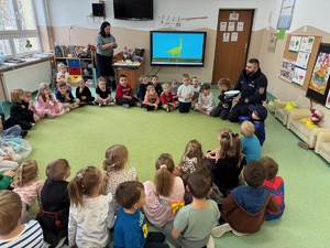 Policjant ruchu drogowego siedzący wśród przedszkolaków na dywanie