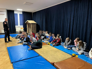 Policjant stojący przed grupą dzieci na dużej sali