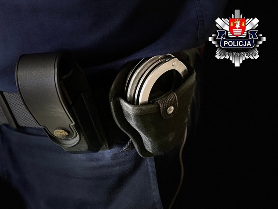 policyjne kajdanki w kaburze na pasie obok kabury z magazynkiem