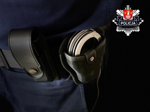 policyjne kajdanki w kaburze na pasie obok kabury z magazynkiem