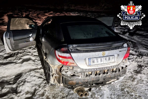 serebrny mercedes zaparkowany na poboczu na zalegającym śniegu z oderwanym zderzakiem