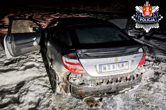 serebrny mercedes zaparkowany na poboczu na zalegającym śniegu z oderwanym zderzakiem