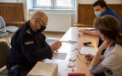 Siedzący na fotelu policjant który wypełnia ankietę