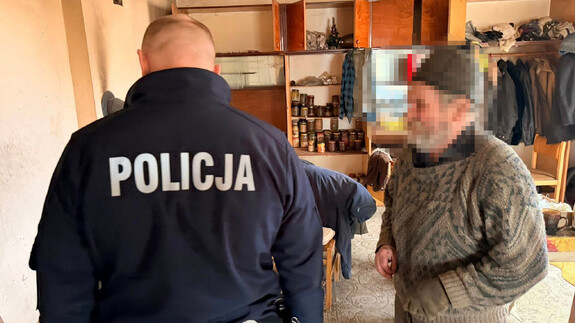 Dzielnicowy u seniora w domu podczas wizuty zerka na jego piec