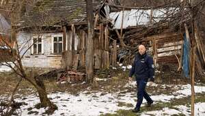 Dzielnicowy wracający z wizyty a za nim drewniana chatka