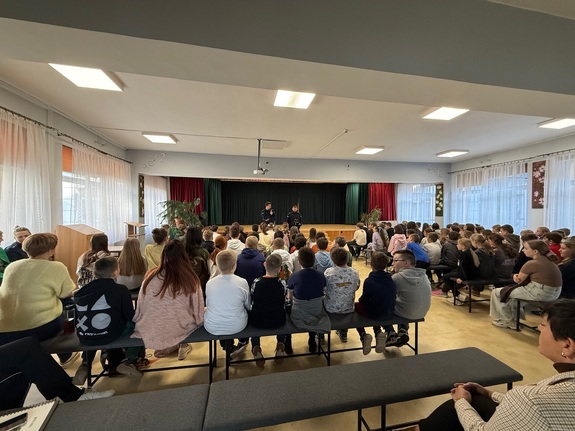 Wypełniona sala dziećmi słuchającychy dzielnicowych