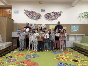 Dzieci trzymające memory z grafikami i stojący obok nich policjanci