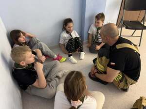 Strażak siedzący przed grupa dzieci