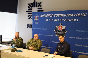 Zastępca Komendanta Powiatowego Policji w Suchej Beskidzkiej siedzący z przedstawicielami straży granicznej