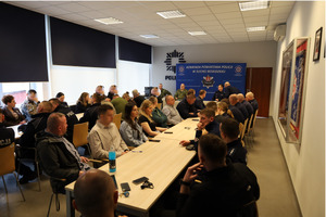 Siedzący funkcjonariusze policji z powiatu suskiego słuchający przedstawicieli straży granicznej siedzącymi przed nimi