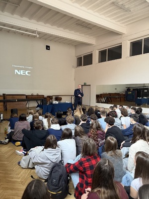 Policjant z mikrofonem przemawiający do uczniów