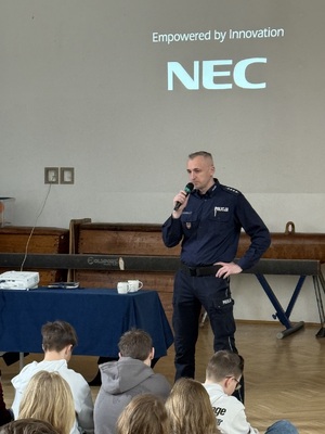 Policjant prowadzący prelekcje stojący z mikrofonem