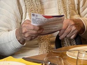 Seniorka trzymająca ulotki prewencyjne