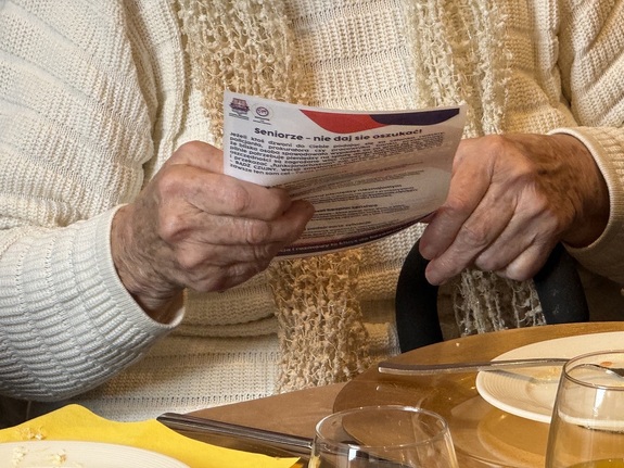 Seniorka trzymająca ulotki prewencyjne