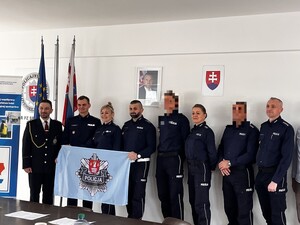 policjanci pozujący do zdjęcia z flagą a na niej logo suskiej komendy