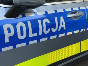 zdjęcie drzwi bocznych kierowcy oznakowanego radiowozu z napisem Policja
