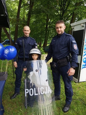 Dzielnicowi pozujący do zdjęcia z chłopczykiem przebranym w strój policjanta
