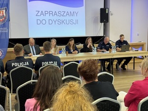 Siedzący organizatorzy i dzielnicowi oraz uczestnicy debaty