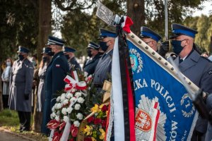 Cmentarz. Policjanci ze sztandarem. Na drugim planie komendant wojewódzki.