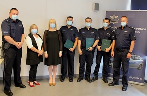 Nagrodzeni policjanci stojący z podziękowaniami w obecności przedstawicielek banku oraz komendantów