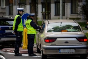 policjant i policjantka ruchu drogowego w trakcie kontroli samochodu marki renault