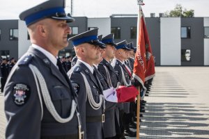 policjanci stojący w szyku ze sztandarem i złożona flagą