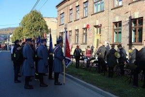 policjanci stojący ze sztandarem wraz z innymi pocztami przed budynkiem prokuratury