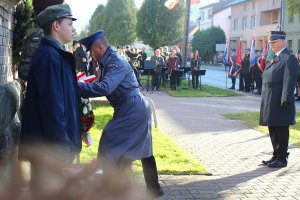 policjant skladający wieńce przed tablicą upamiętniająca postac marszałka j.piłsudskiego