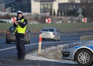 Policjant mierzący prędkość na drodze miernikiem laserowym