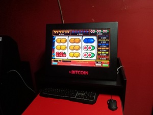 maszyna przypominająca komputer z wyświetlającą grą z owocami oraz napisem na obudowie bitcoin
