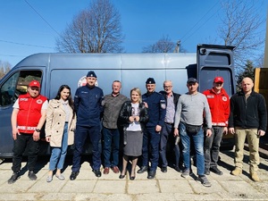 pracownicy policji i policjanci przy samochodzie pozują do zdjęcia