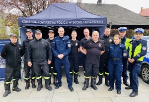 pozujący do zdjęcia policjanci i strażacy przy stoisku kpp sucha beskidzka