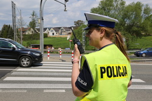 policjanta stojąca przy przejściu dla pieszych i trzymająca w ręku przy twarzy radiostację