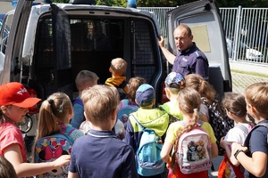 policjant prezentuje grupie dzieci radiowóz