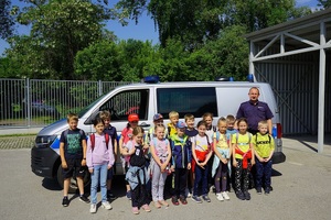 policjant wraz z grupa dzieci pozują do zdjęcia przy radiowozie