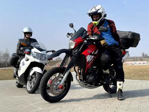 Policjant w kasku na służbowym motocyklu i mężczyzna – cywil w kasku na motocyklu supermoto