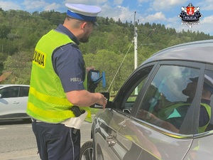 policjant wrd pokazujący kierowcy samochodu wynik prędkości na mierniku laserowym