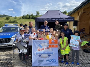 pozujące do zdjęcia dzieci z policjantami i żołnierzem wraz z tablica kręci mnie bezpieczeństwo nad wodą