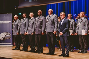 stojący w szeregu policjanci i kapelan policjantów przed wręczeniem związkowych medali