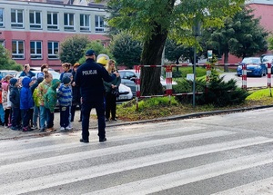 policjant stojący przed grupą dzieci na przejściu dla pieszych