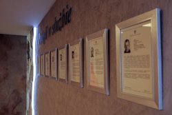 Zdjęcie przedstawiające specjalne miejsce w Komendzie wojewódzkiej gdzie znajdują się powieszone na ścianie w srebrnych ramkach informacje ze zdjęciami po poległych policjantach z garnizonu Komendy Wojewódzkiej Policji w Krakowie, którzy polegli w czasie służby.