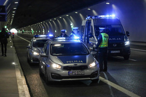 tryz radiowozy na światłach uprzywilejowania w tunelu a obok policjanci
