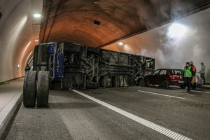 rozbity autobus położony na lewym boku na środku jezdni w tunelu