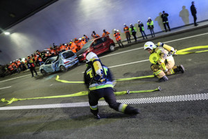 strażacy rozwijający węże na drodze w tunelu