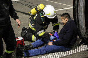 strażak udzielający pomocy osobie leżącej na asfalcie jadący samochód ciężarowy podczas podczas ćwiczeń w tunelu