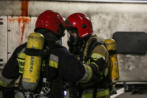 strażacy ubrani w maski tlenowe jadący samochód ciężarowy podczas podczas ćwiczeń w tunelu
