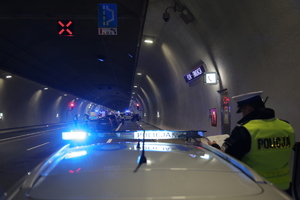 policyjny radiowóz a w tle stojące samochody w korku podczas ćwiczeń w tunelu
