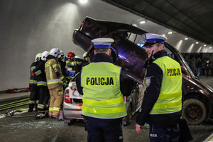 policjanci wykonywujący czynności na tle rozbite samochody i strażacy podczas ćwiczeń w tunelu