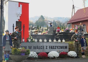 pomnik na cmentarzu w suchej beskidzkiej przy którym stoi warta strzelców oraz harcerzy